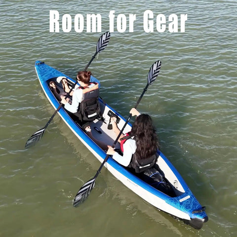 Two people paddling the Razorlite 473rl Inflatable Drop Stitch Kayak Pro Package on a lake, showing tandem seating and gear space.