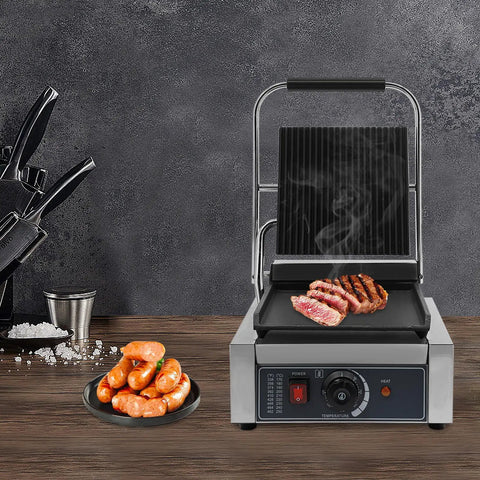 1800W Commercial Panini Grill Press With Stainless Steel Body And Cast Iron Plates cooking sausages and grilled meat on a countertop.