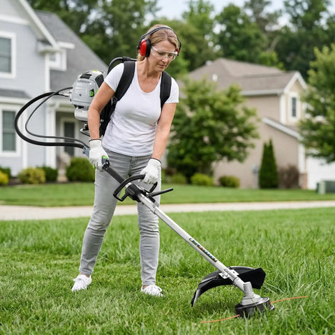 Person using 6 In 1 Backpack Gas Powered Weed Eater Kit With 52cc 2 Stroke Engine Includes String Trimmer Hedge Trimmer Pole Saw Brush Cutter Blade And Safety Lock Shoulder Strap For Lawn Trimming on grass.