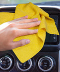 Yellow microfiber cleaning cloth on car dashboard, close-up.