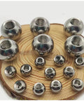 Front view of stainless steel threaded piercing balls on a wooden display; M8 bore, diameters 15–60 mm.