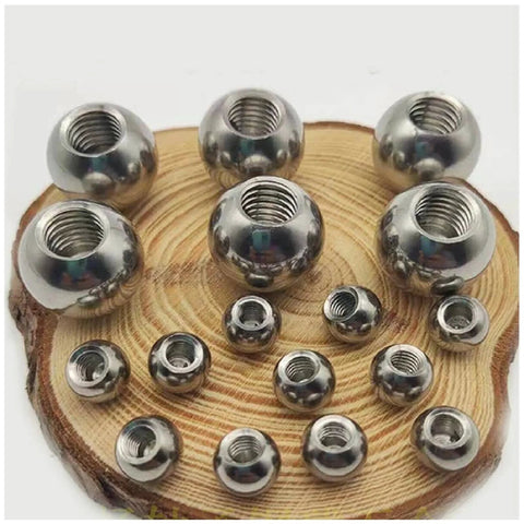Front view of stainless steel threaded piercing balls on a wooden display; M8 bore, diameters 15–60 mm.