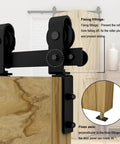 Close-up of black roller and fixing fittings on 36 Inch Bi Folding Sliding Barn Door Hardware Kit With Carbon Steel Rail And Two Rollers For Closet Doors Up To 30 Inch Opening Built Tough Heavy Duty Construction Ready For Easy Install And Smooth Operation And Durable Everyday Use installed on a wooden door.