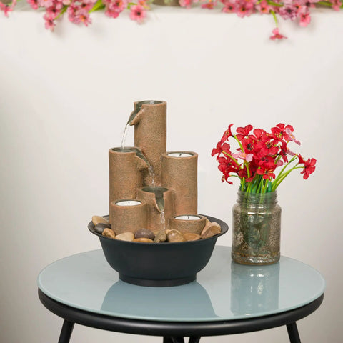 Indoor Tabletop Tiered Water Fountain With 3 Candles, 11 Inch Brown on round glass table with flowers and rocks
