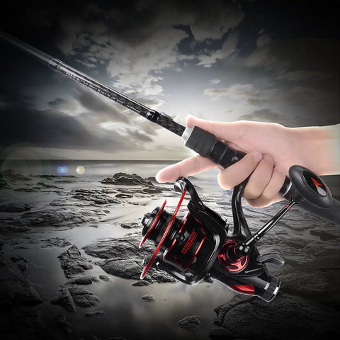 Angler holding Beast Mode Baitfeeder III Spinning Fishing Reel Size 6000 in action on rocky shoreline, showcasing design and grip.