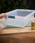 Person applying Thick Rubberized Waterproof Tape That Patches And Seals Leaks Like A Pro Anywhere Underwater Ready Indoor Outdoor Use Great For Roofs Plumbing Pools And RVs Clear 4 In By 5 Ft Pack Of 1 to a clear plastic container.