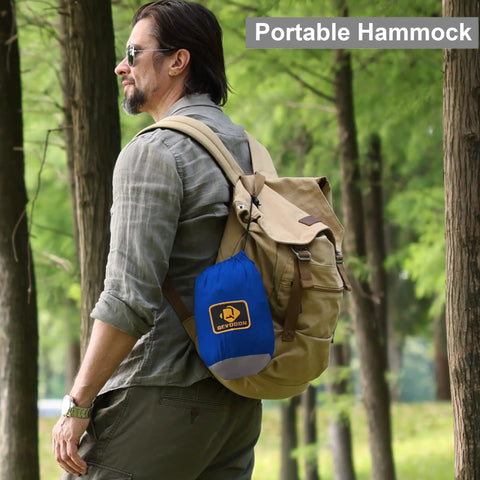 Man outdoors carrying a portable hammock bag with the Camping Hammock With Mosquito Net For Outdoor Travel Portable Lightweight Parachute Nylon Hammock With Tree Straps And D Shape Carabiners Breathable Mesh Net Backpacking Ready For Beach Backyard Patio Hiking