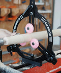 BMWOOD woodturning steady rest MC-FS7 mounted on a lathe; black metal frame with pink roller wheels