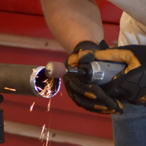 Tough As Nails Straight Pneumatic Die Grinder in use, grinding steel pipe, generating sparks and fine dust, showcasing ergonomic grip.