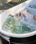 Close-up of 120-Qt Rolling Ice Chest Cooler Cart With Wheels holding bottles and cans in ice, black exterior visible.
