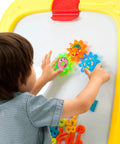 Child playing with colorful magnetic shapes on Mega Size Magnetic Double Sided Kids Easel Built Tough For Endless Creative Sessions Adjustable Height Dry Erase And Chalkboard Art Station.