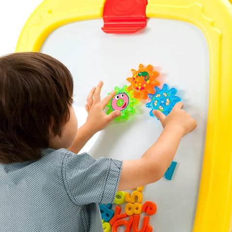 Child playing with colorful magnetic shapes on Mega Size Magnetic Double Sided Kids Easel Built Tough For Endless Creative Sessions Adjustable Height Dry Erase And Chalkboard Art Station.