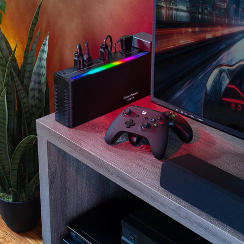 GX950UC Gaming UPS Battery Backup And Surge Protector for PCs with RGB lighting next to gaming setup on desk