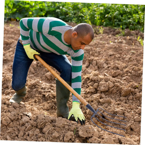 Person using Heavy Duty Garden Fork For Farm Cleanup And Mulching, Versatile Manure Rake in a field.