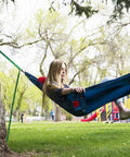Person relaxing in Ultralight Camping Hammock 12 Oz Lightweight Blue Portable Ripstop Polyester 96 By 46 Inch Solo Lounger outdoors.