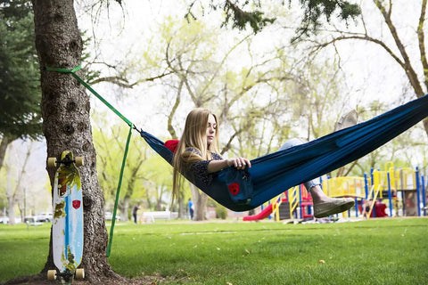 Person relaxing in Ultralight Camping Hammock 12 Oz Lightweight Blue Portable Ripstop Polyester 96 By 46 Inch Solo Lounger outdoors.