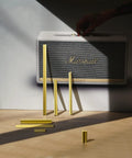 Yellow bars arranged on floor in front of a white and black speaker with a hand reaching towards it, creating a shadowed visual.