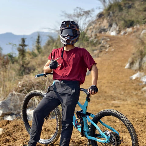 Man wearing Baggy Quick Dry Mountain Bike Pants For Men With Stretch Nylon Spandex, Size 34, in Army Green, standing with bike on trail.