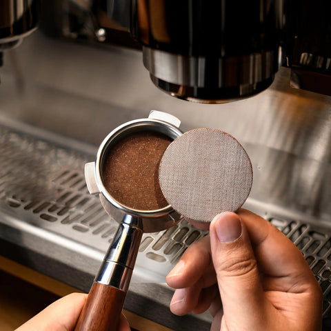 Close-up of 54mm stainless steel bottomless espresso portafilter with rosewood handle and puck screen