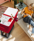 80QT Rolling Cooler On Wheels With Bottle Opener Outdoor Beverage Cooler next to a woman lying on a couch, ice-filled, red color