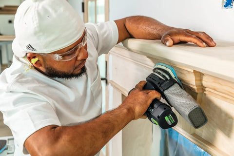 Person using Granat Profile Delta Sanding Pads Set Of 10 With Flexible Foam Backing on wood molding, corner sanding detail.