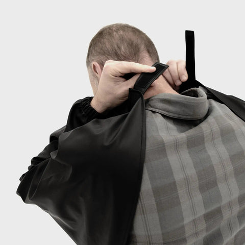 Person adjusting Heavy Duty Butchering Apron With Full Arm Coverage, Waterproof Vinyl Material, Elastic Cuffs, One Size, Black