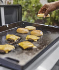 Heavy Duty Weber Griddle Press For Perfect Bacon, Smash Burgers And Crispy Paninis on a hot griddle with burgers and buns.