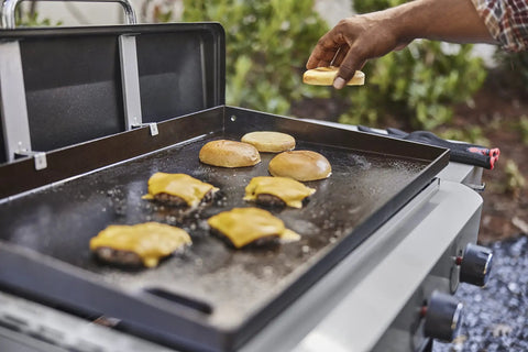 Heavy Duty Weber Griddle Press For Perfect Bacon, Smash Burgers And Crispy Paninis on a hot griddle with burgers and buns.