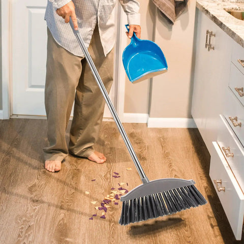 Person using Dark Grey Angle Floor Broom With Long Stainless Steel Handle And Dense Stiff Bristles to clean kitchen floor.