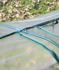 Close-up of 11 By 3 By 2.5 Ft Mini Greenhouse Portable Tunnel with steel frame and clear plastic cover on grass.