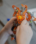 Rugged Metal Erector Set Build Kit For Adults And Teens, 389-Piece STEM Toy To Build A Robot Or Excavator, Dope Educational Engineering Craft For Advanced Kids And Hobbyists; hands holding metal robot build