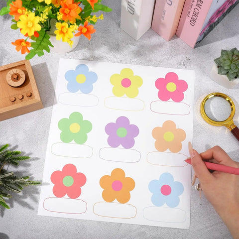 Sheet of 180 Pcs Flower Name Tag Stickers Set For Back To School with pastel floral designs on a desk.