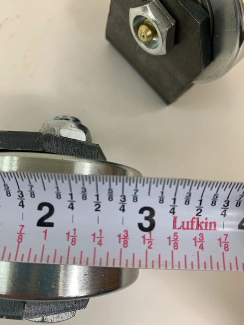 Close-up of Set Of 2 Weld On Trailer Tail Drag Casters With Solid Steel Rollers And Greasable Axle 1.5 Inch Wide, includes tape measure.