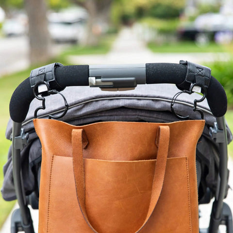 Brown leather bag hanging on stroller with Stroller Hooks 2 Pack Carabiner Clips For Baby Gear Heavy Duty Universal Stroller Clips