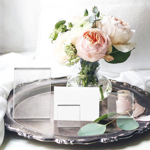 Set Of Six Clear Acrylic Styling Blocks And Flat Lay Props Ideal For Wedding Centerpieces And Product Shoots, showcases blocks next to flowers.