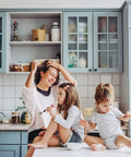 Mother and two children enjoying time together in a modern kitchen with gray cabinets and white countertops.