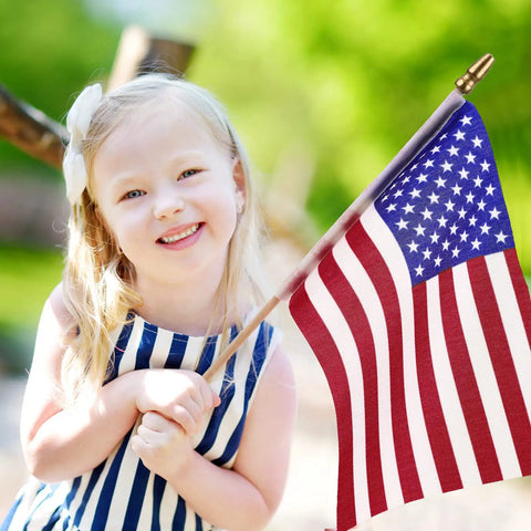 Child holding 50 Pack USA Stick Flags 12 By 18 Inch Small Flags With Wooden Poles And Spear Tips for outdoor celebration