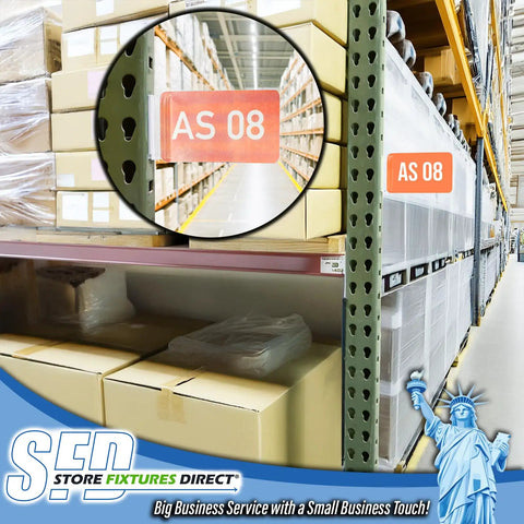 Heavy Duty Warehouse Aisle Sign Holders For Pallet Rack Upright With Flexible Hinge 50 Pack visible on a rack in a warehouse.