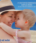 Mack's Pillow Soft silicone earplugs, orange, worn by child at the beach