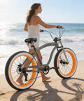 Woman walking on beach with Fat Tire Cruiser Bike With 7 Speed Shimano, iconic stretch chopper frame in a greyish orange finish
