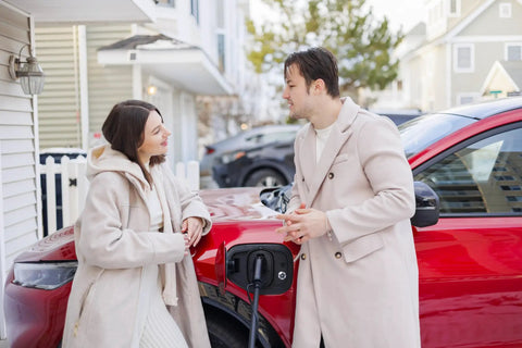 Couple discussing beside a red car with Heavy Duty Level 2 EV Charger 48 Amp Wall Mount Station With J1772 Plug And Tesla NACS Adapter 240 Volt NEMA 14 50 Hardwire Ready 30 FT Cord.