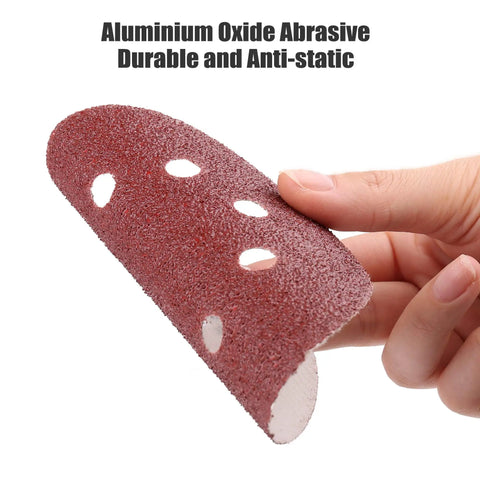 Hand holding 110 Pack 5 Inch 8 Hole Sanding Discs Set With Hook And Loop Aluminum Oxide Pads, curved to show flexibility.