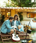 Family sitting outdoors by a campfire with 58 Foot Solar String Lights Outdoor With Remote Control illuminated above them.