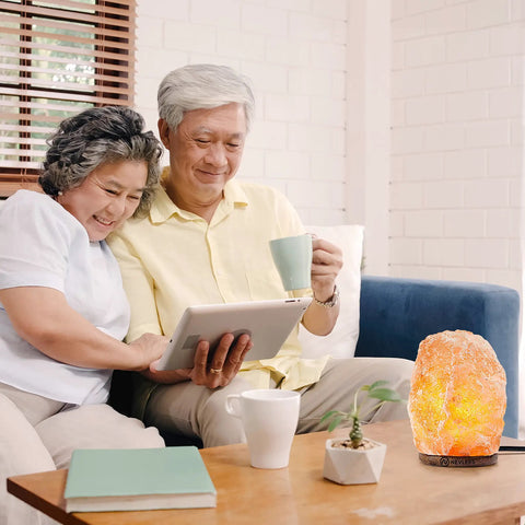 Two Pack Pink Himalayan Salt Lamps With Dimmer Cord And Bulb on table, glowing beside couple on couch with tablet and mug