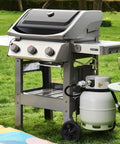 Side view of gas grill with Three Feet Propane Regulator Hose With Tank Gauge For Universal Gas Grill Regulator, set on grass.
