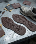 2 Pack Heavy Duty Rubber Sole Replacement Patches For Work Boots And Casual Sneakers on a workshop table with tools and sneaker.