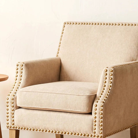 Twenty Piece Pack Of Solid Brass Upholstery Tacks With Top Shelf Hold And A Sweet Vintage Look For Furniture Projects Smooth Woodcraft Crafts And Easy Diy Home Decor Fixes In Classic Gold Finish And One Half Inch Heads on a beige armchair.