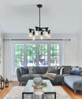 Six Light Matte Black Modern Farmhouse Chandelier With Clear Glass Shades adjustable hanging in a stylish living room setting.