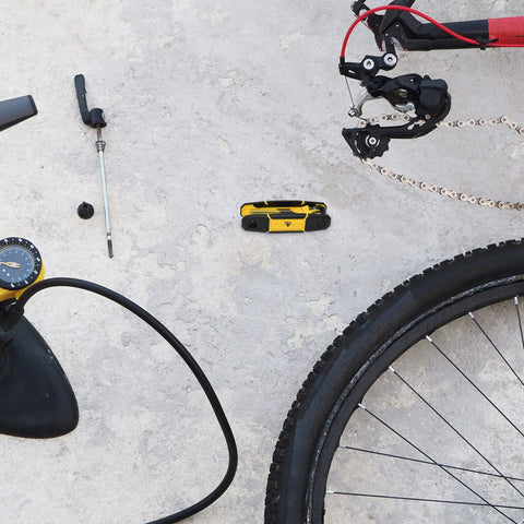 Folding Hex Key Set With Metric And SAE Allen Wrenches, Heat Treated S2 Finish, shown next to bicycle tools on concrete
