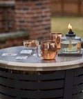 Tabletop Fire Pit Cover For Patio Pits 25.6 Inch Durable Stainless Steel Lid Weather Resistant Outdoor Fire Pit Protector Converts Fire Pit Into A Table For Chill Entertaining Gold with drinks and cards on top